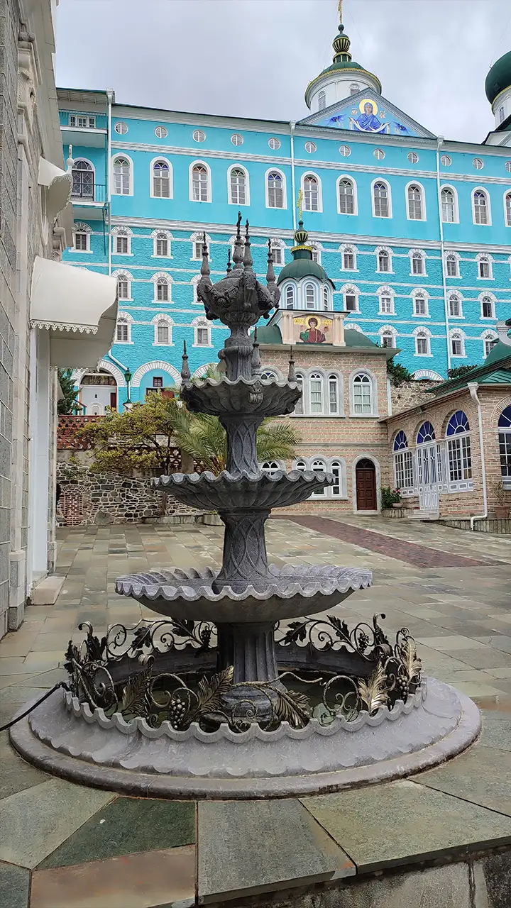 Каменный фонтан во дворе Пантелеймонова монастыря на Афоне, на фоне голубого корпуса